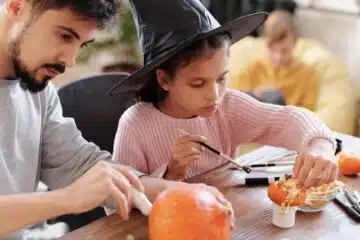 father and daughter decorating pumpkins for halloween